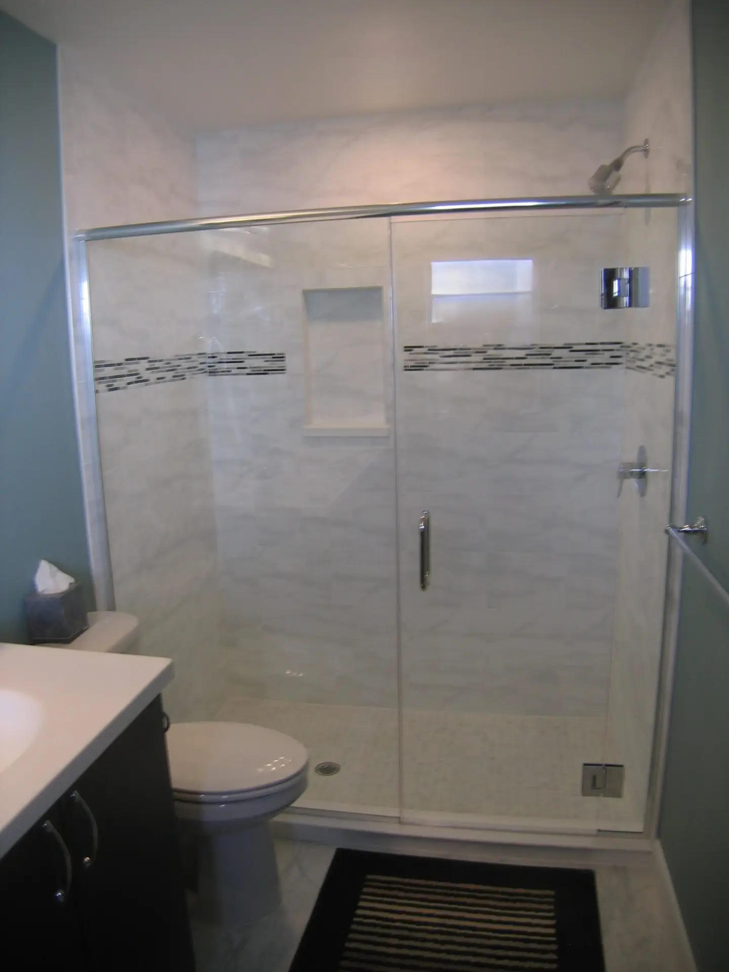 A new shower for him with horizontal tile and a frameless hinged enclosure