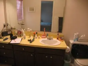 Before photo of his cluttered bathroom vanity with dated sink.