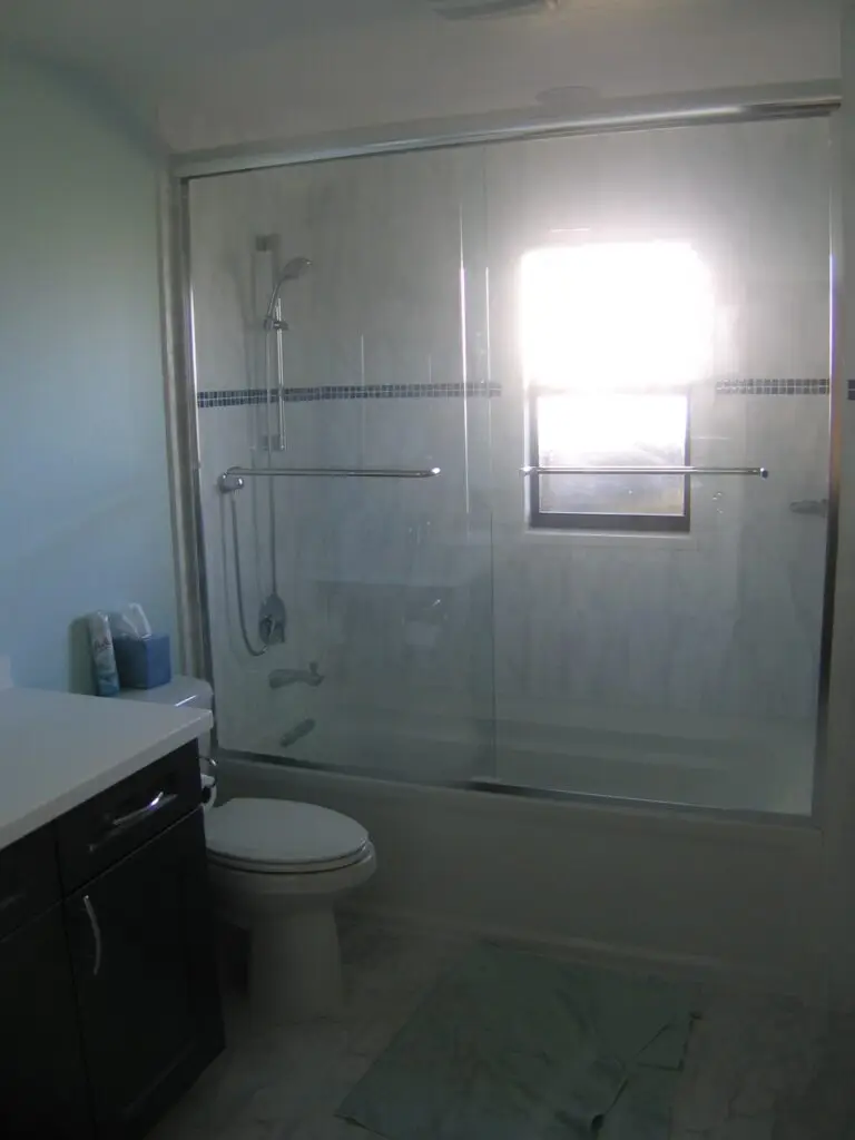 Her new bathroom with a 5ft tub, glass enclosure, and vertical tile pattern.