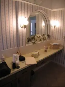 Outdated guest bathroom with dark vanity and floral wallpaper before remodel