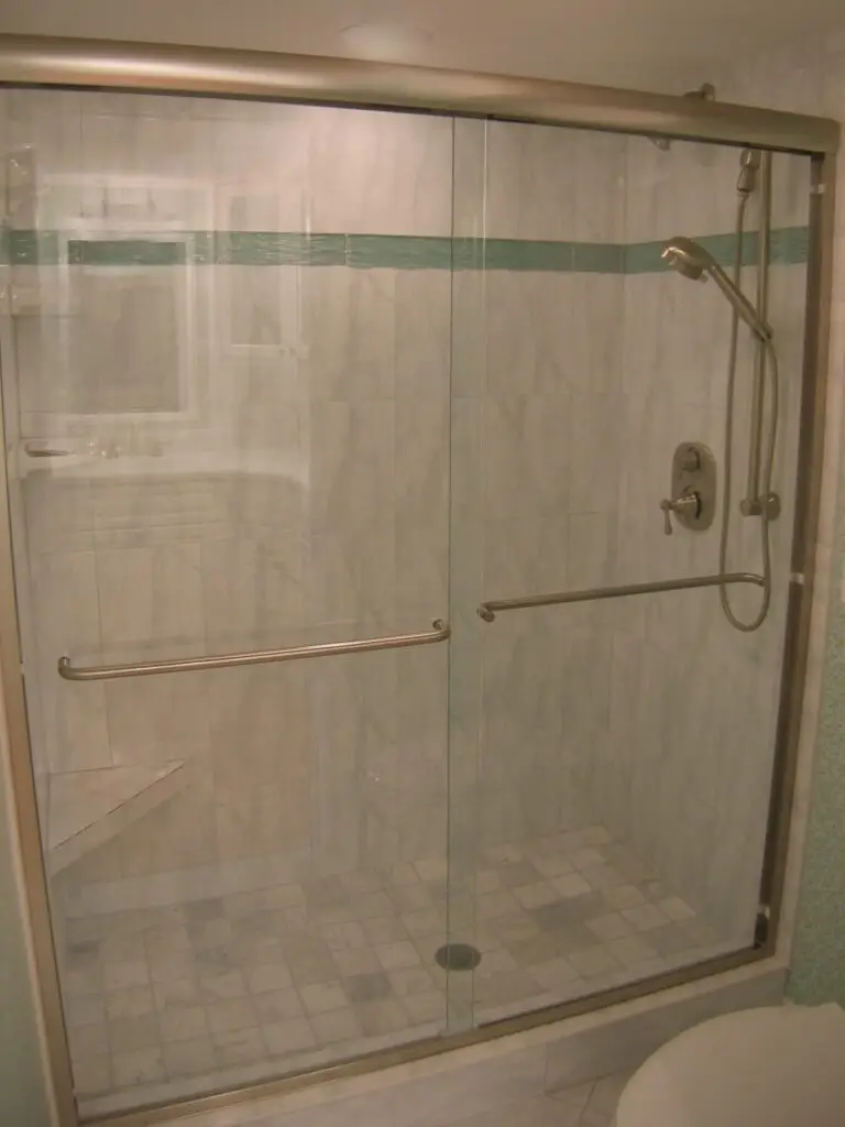 Walk-in shower in a Perico Island master bathroom with a built-in seat, grab bars, and large easy-to-clean tiles