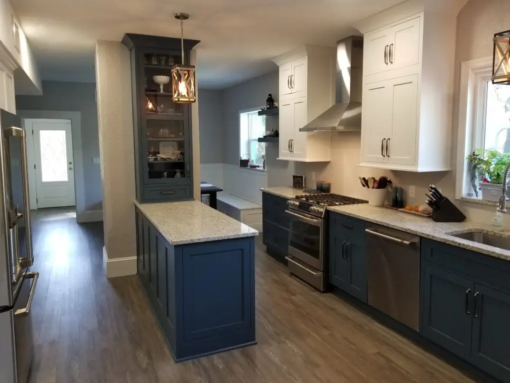 A professionally remodeled blue and white kitchen with stainless steel appliances and granite countertops