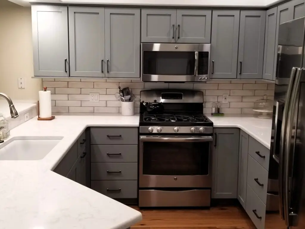 a modern kitchen with gray cabinets, white quartz countertop and ergonomic design