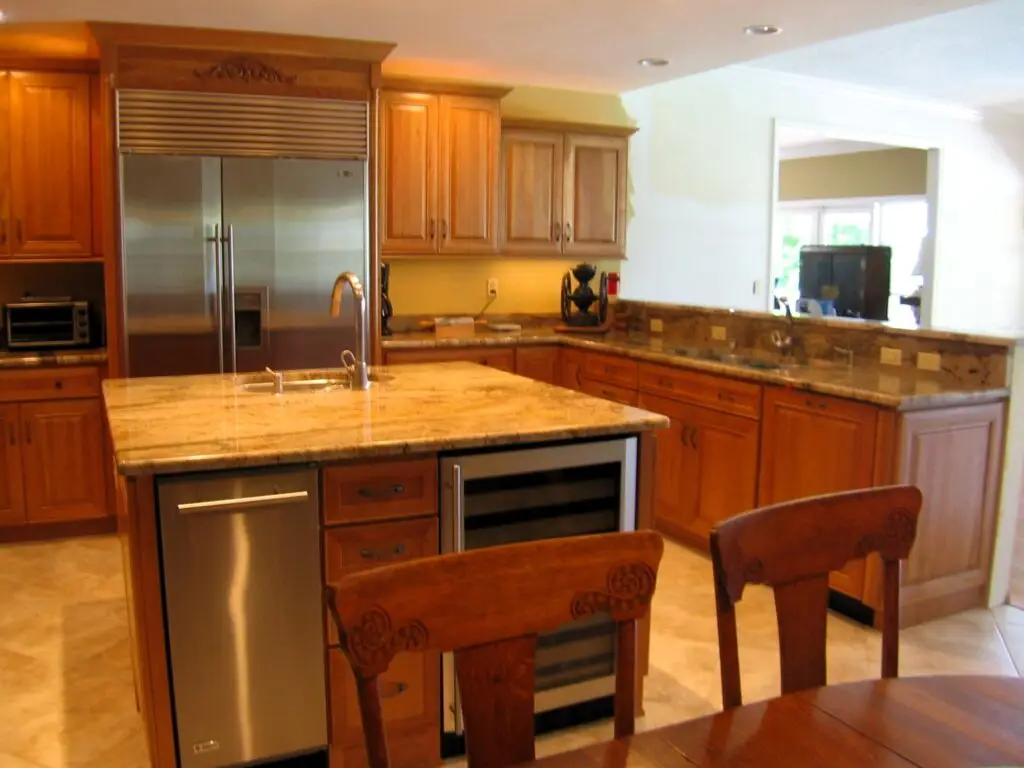 A large island for entertaining equipped with an ice maker and wine chiller on Snead Island with cherry cabinets and granite countertops