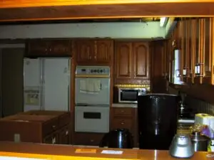 Before photo of a large and dated kitchen in Palmetto with white appliances and oak cabinets