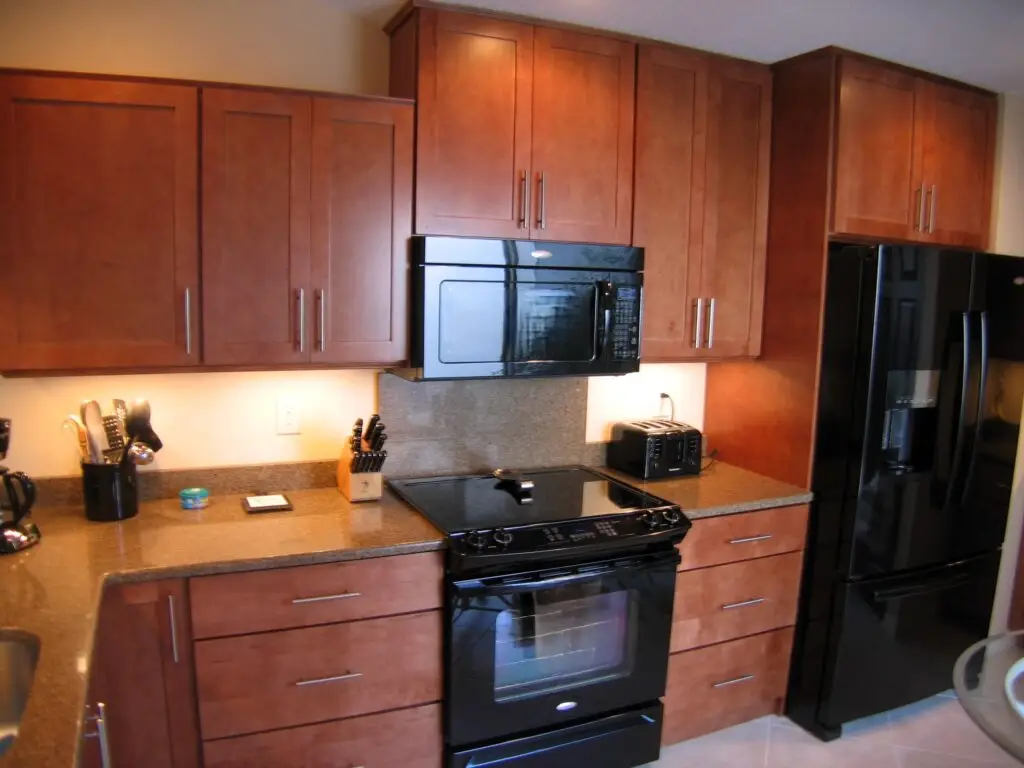 Close up of new range and microwave with full height chocolate brown quartz backsplash in a Bradenton kitchen