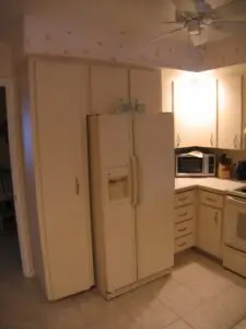 Before photo of a dated kitchen with soffits and wallpaper
