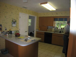 Before photo of a characterless kitchen with 70s cabinets and a basic peninsula