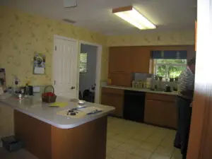 Before photo of a characterless kitchen with 70s cabinets and a basic peninsula