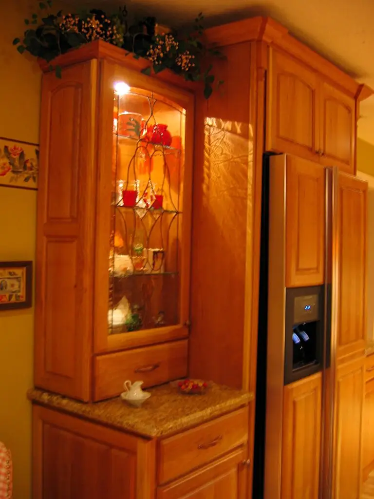Custom leaded glass cabinet inserts with interior lighting flanking a built-in refrigerator