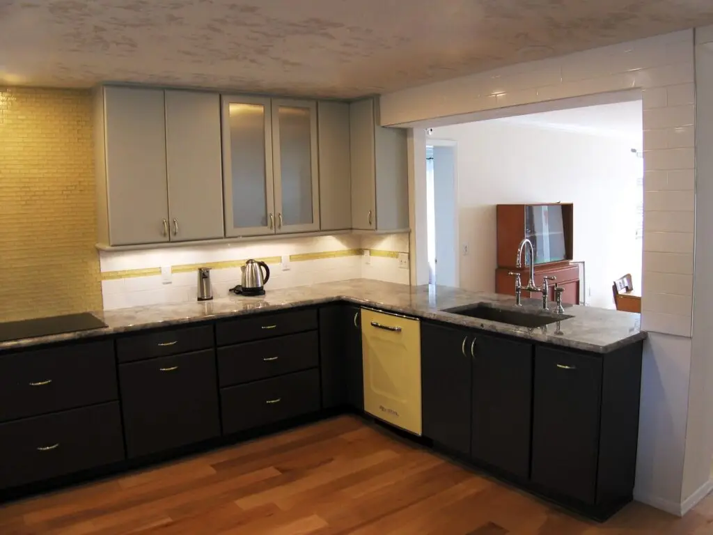 Retro yellow dishwasher gives a pop of color to the dark gray base cabinets and cool gray upper cabinets in this remodeled kitchen