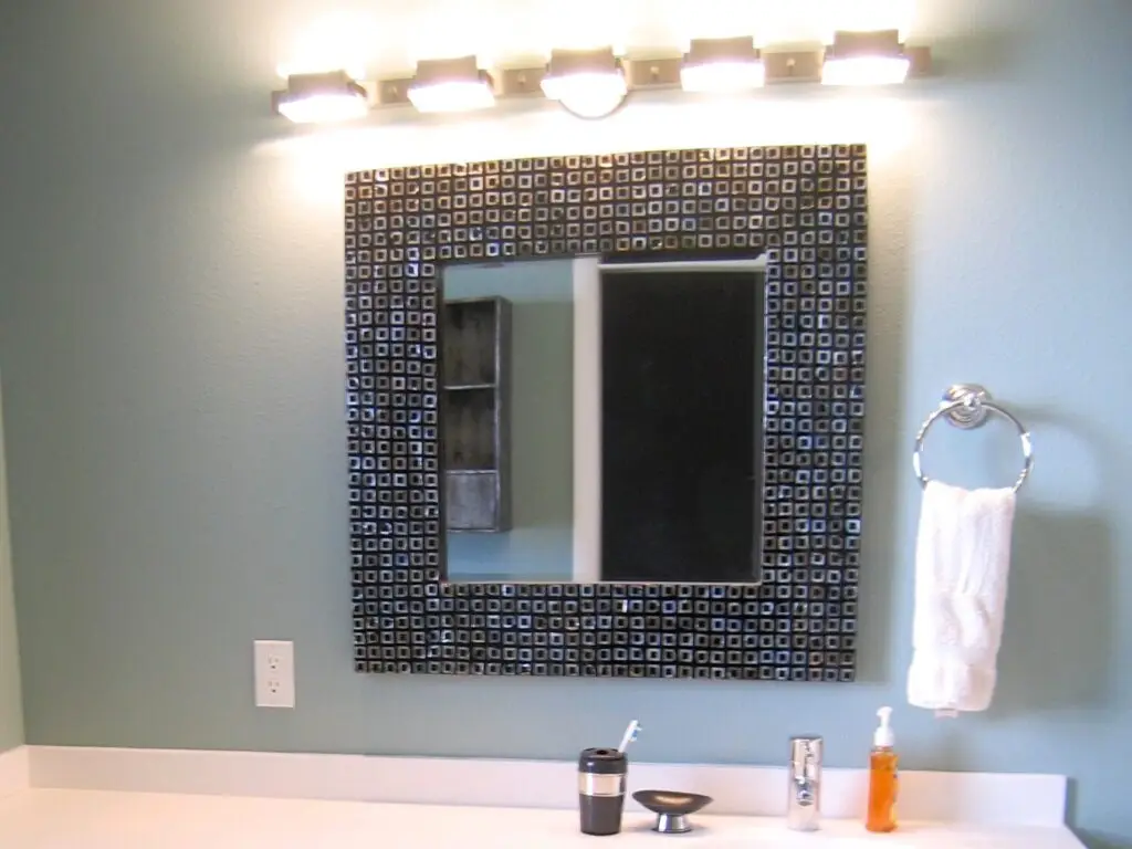 A beautifully lit vanity area in a small bathroom with both overhead recessed lighting and wall-mounted fixtures