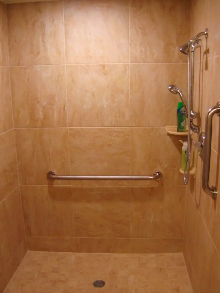 A modern, small bathroom floor with seamless large-format terra cotta tiles, showing minimal grout lines