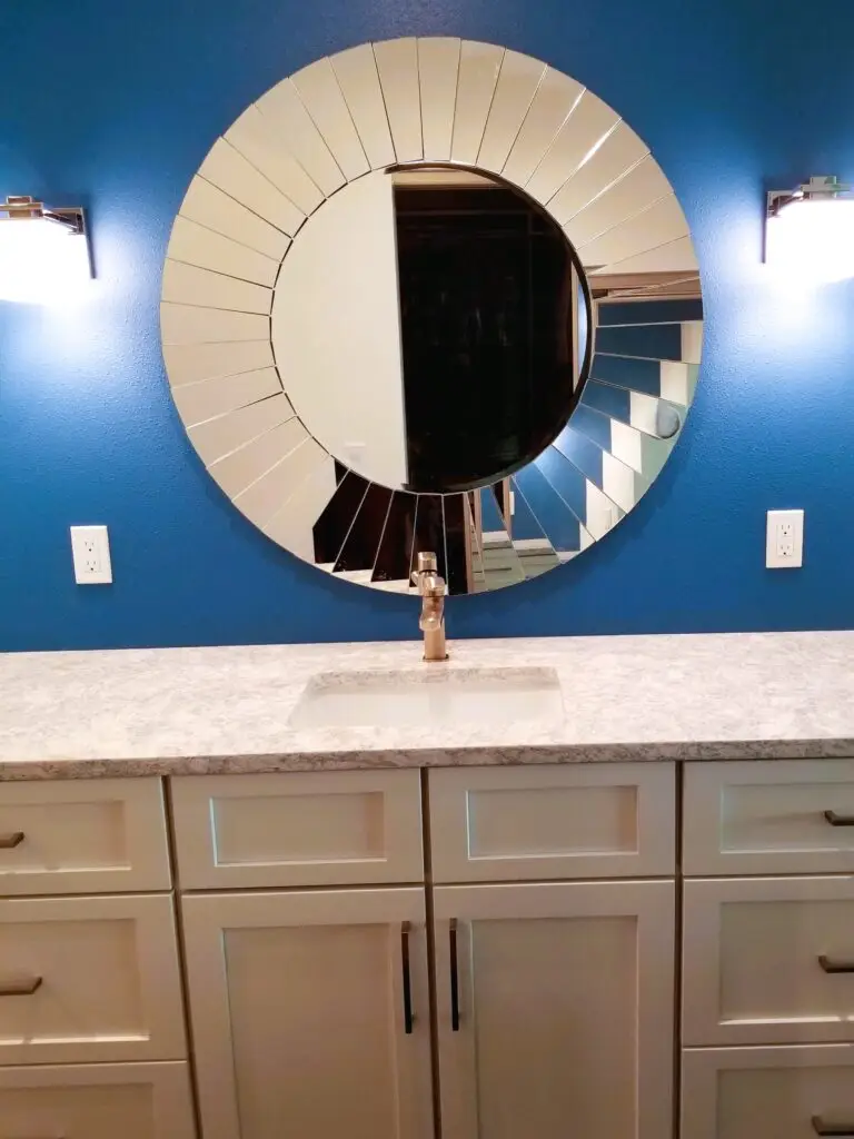A modern vanity in a small bathroom with bold blue walls and white toned vanity top