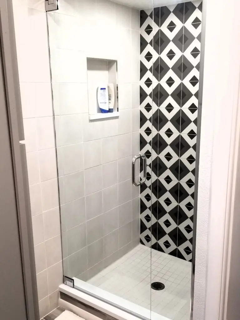A small, modern shower with a single, bold geometric tile wall
