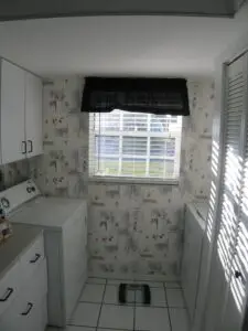 Before photo, the washer and dryer flanking a window at the end of a narrow galley kitchen