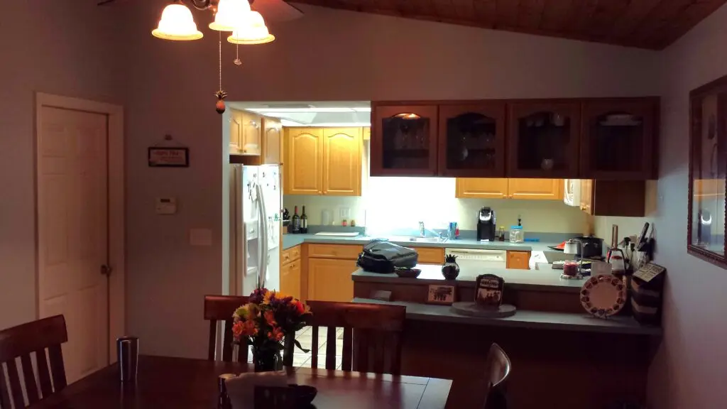 A before photo showing golden oak cabinets with turquoise laminate counters and a closed in layout