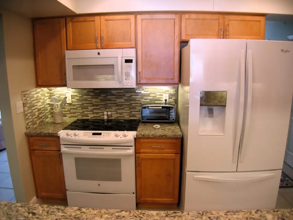 Cabinets in a Butterscotch stain with white appliances in a newly remodeled kitchen