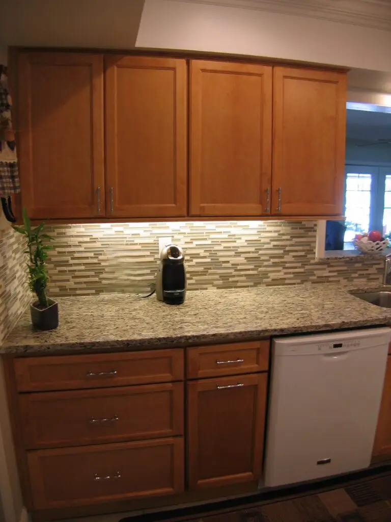 Santa Cecilia granite countertops and Eclipse linear tile backsplash in a remodeled kitchen on a budget