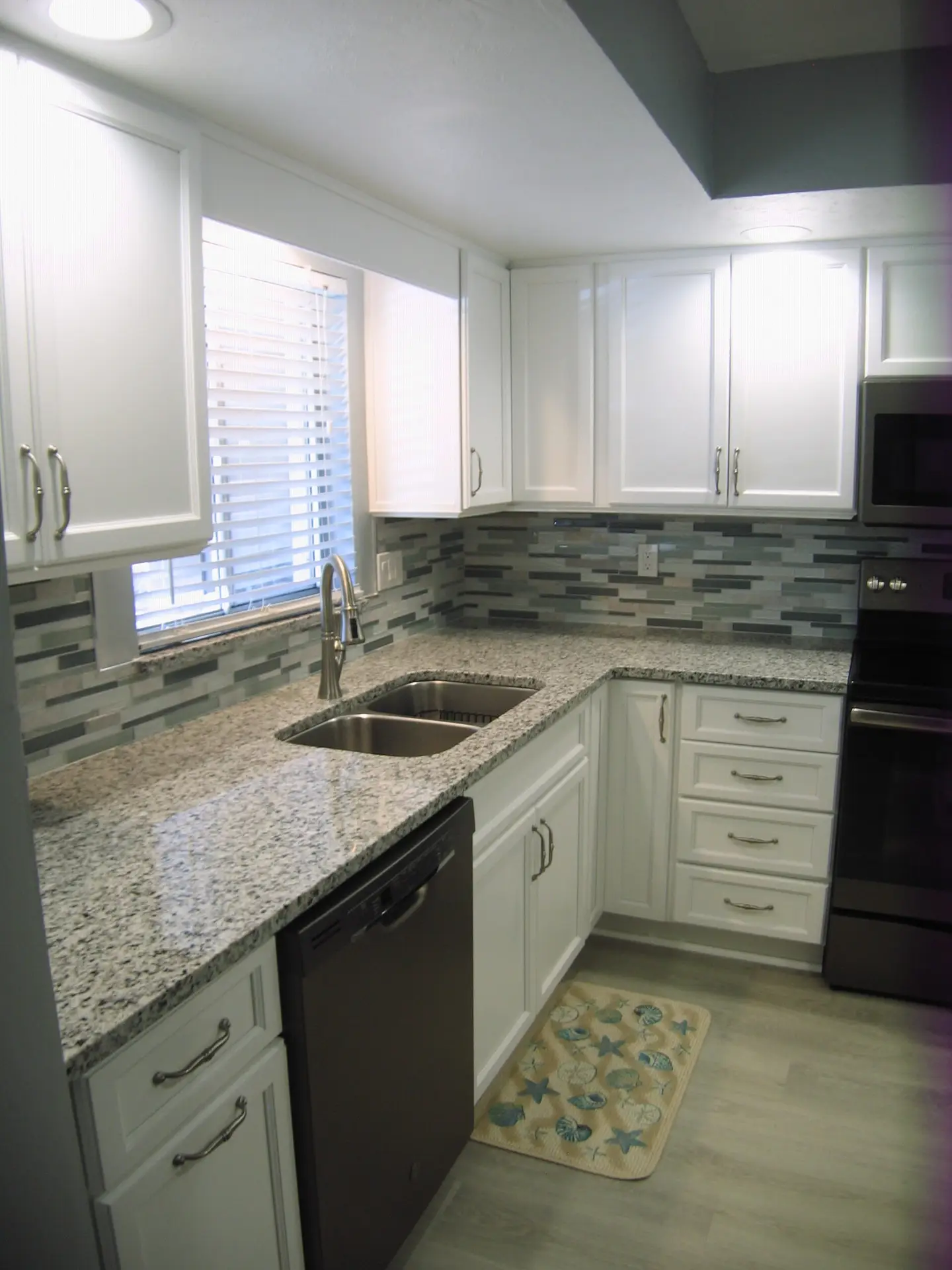 White shaker cabinets and Bianco Sardos granite of a recently completed kitchen remodel at Bayshore on the Lake in Bradenton