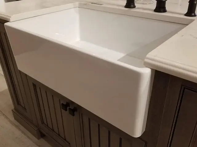 White modern cast iron farmhouse kitchen sink with a deep single bowl and a classic apron front