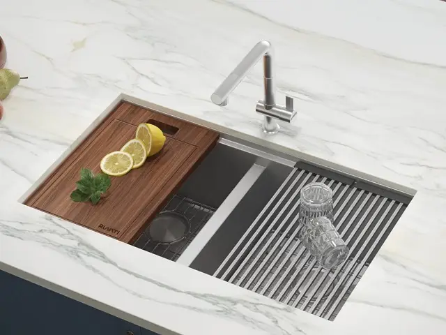 Multi-functional stainless steel galley kitchen sink with integrated accessories like a cutting board and drain rack