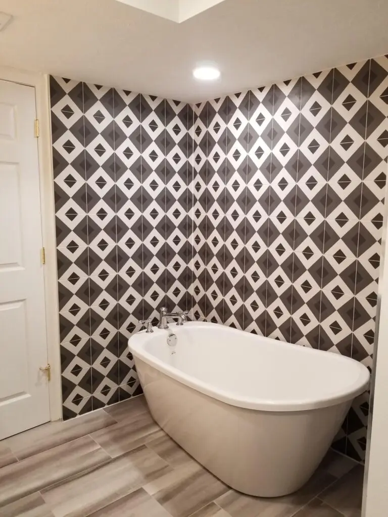 A pure white vessel tub contrasts beautifully with the bold focal point walls adorned with bold geometric tile