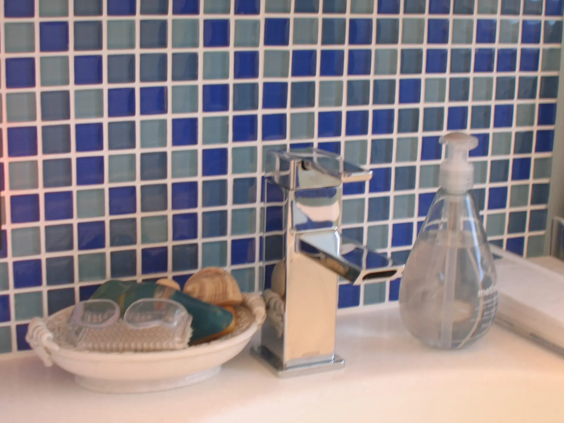 Sarasota master bathroom designed and remodeled by Duncan's Creative Kitchens with blue mosaic tile behind a vanity sink