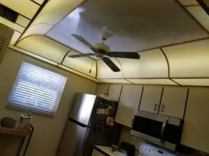 A Before photo featuring a dated and dark dome ceiling with florescent lights