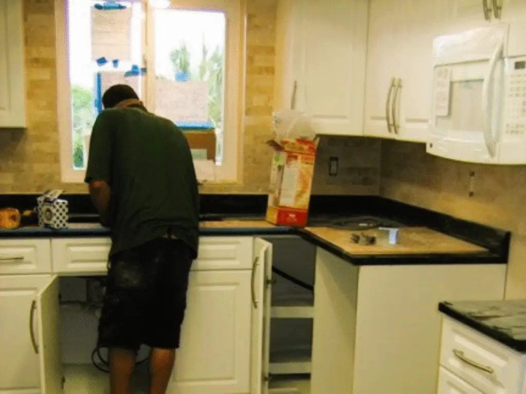 A building permit for a kitchen remodel is displayed prominently in the window at a construction site