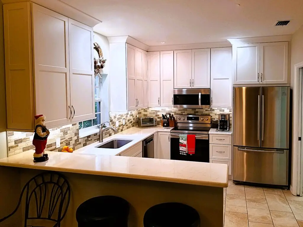 A finished, modern kitchen with new appliances, countertops, and a full tile backsplash, showing the final result of a successful remodel