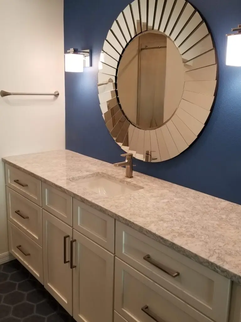 A newly remodeled master bathroom vanity in a Bradenton condo with a stunning royal blue accent wall and sunburst mirror