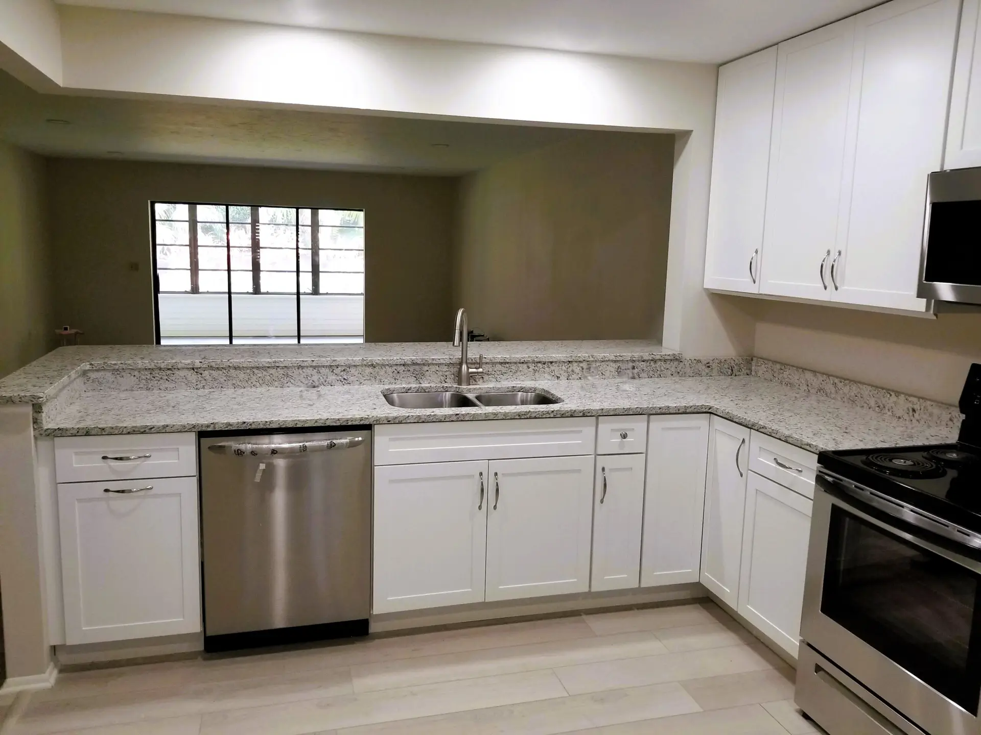 Image of modern white shaker cabinets and white ornamental granite in a renovated Bradenton kitchen