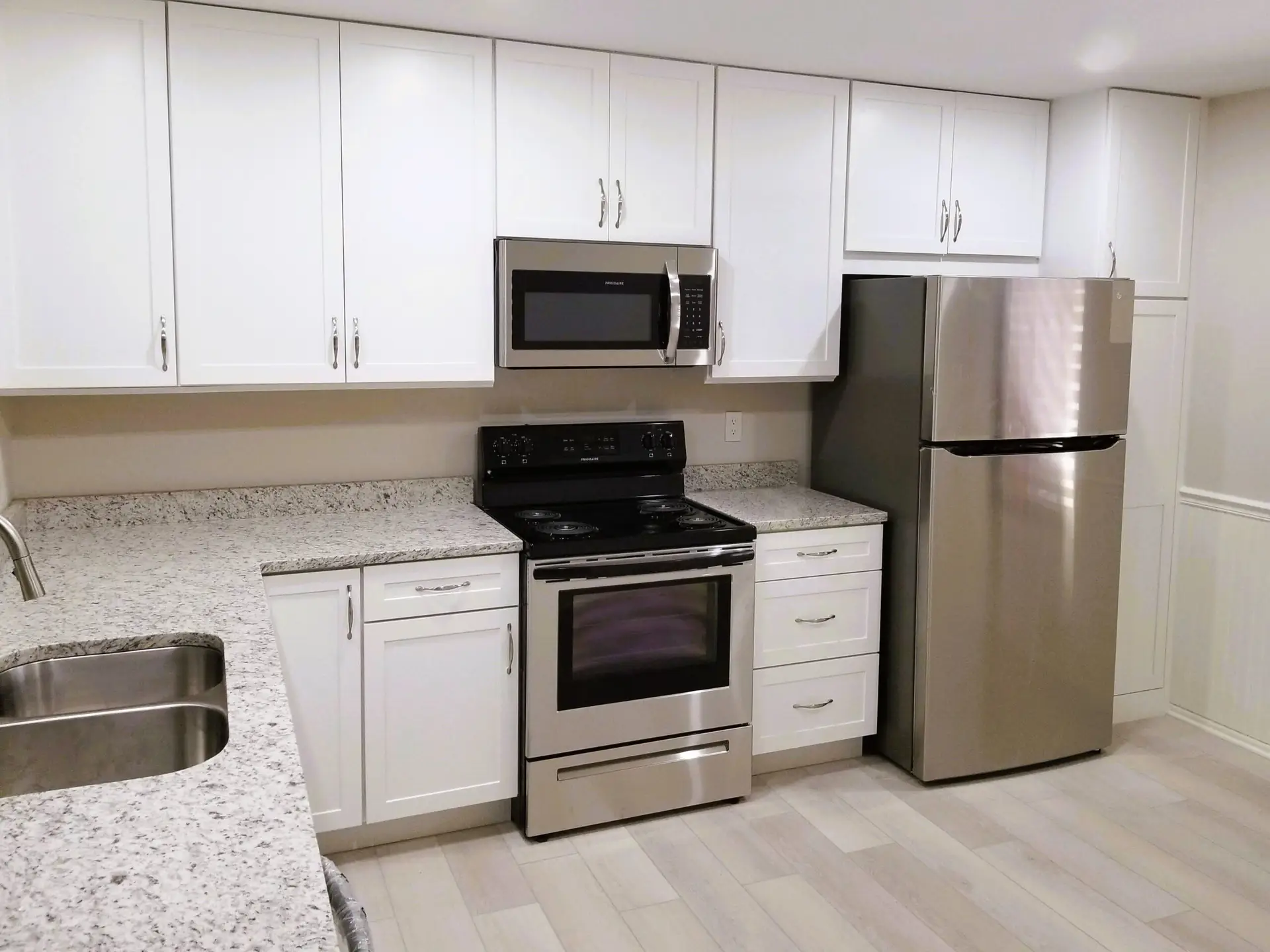 Image of newly installed white mantra cabinets and granite countertops