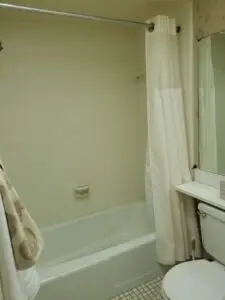 Outdated bathtub with shower curtain in master bathroom