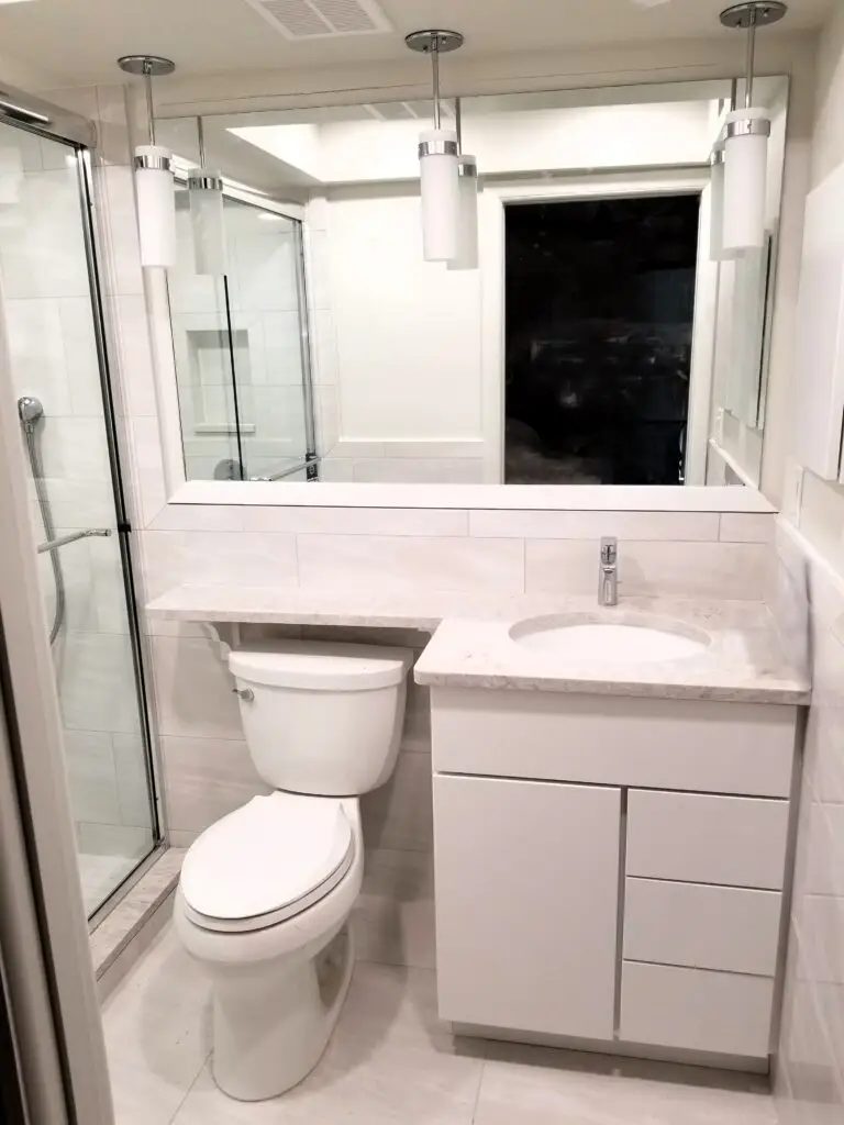 Updated master bathroom with pendant lights and framed mirror