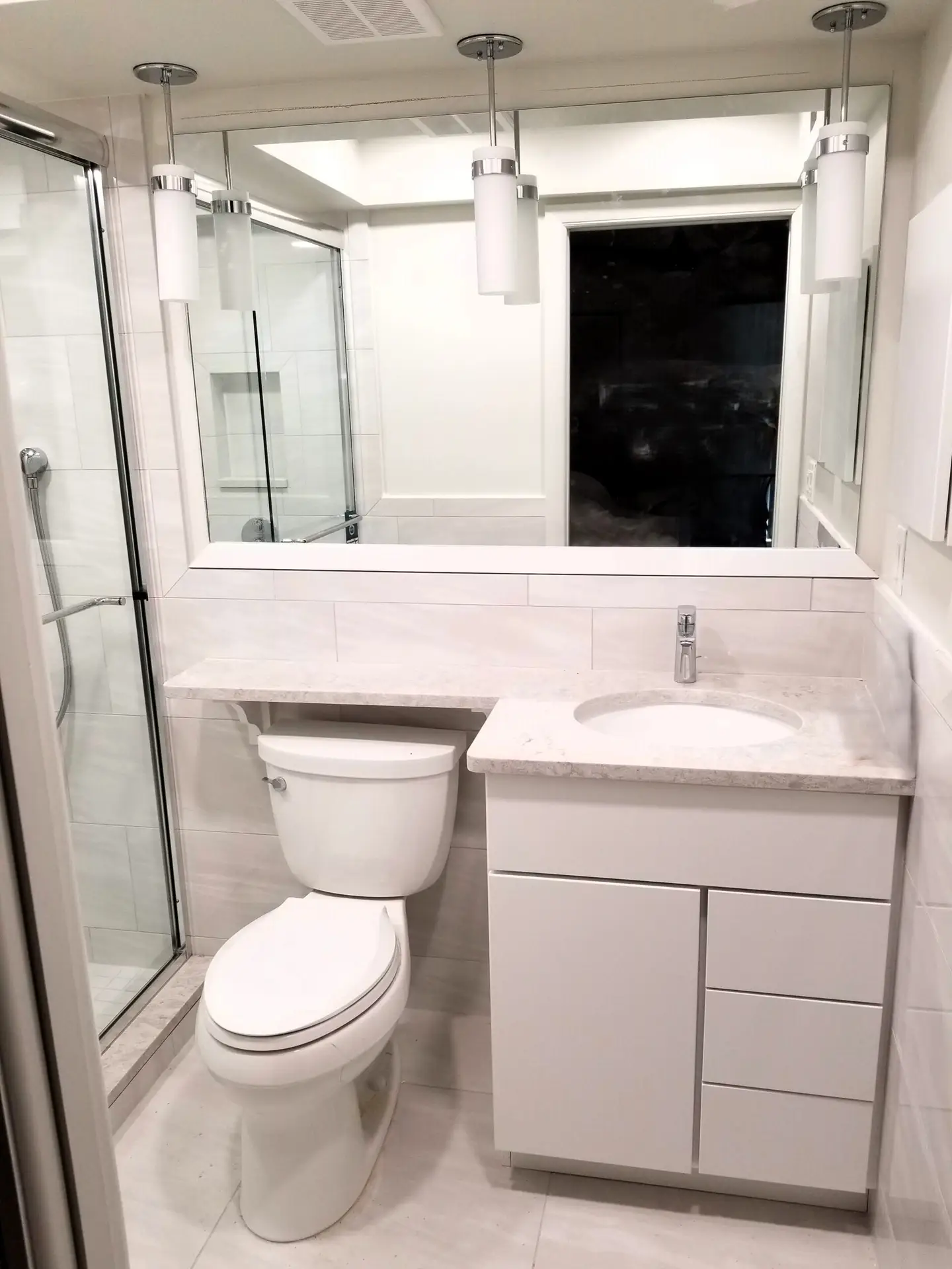 Updated master bathroom with pendant lights and framed mirror