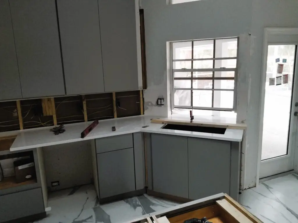 close up shot of a new quartz countertop being carefully placed onto installed kitchen cabinets