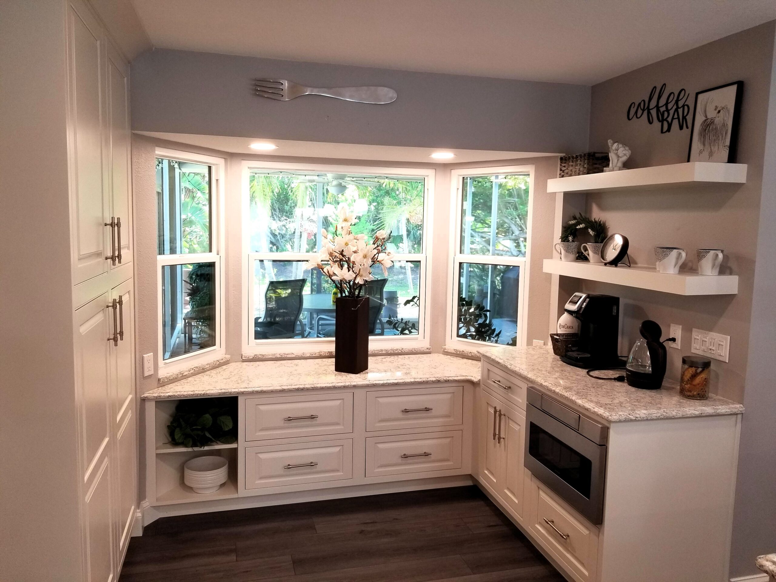 Auxiliary storage area with coffee bar and custom cabinetry below bay window