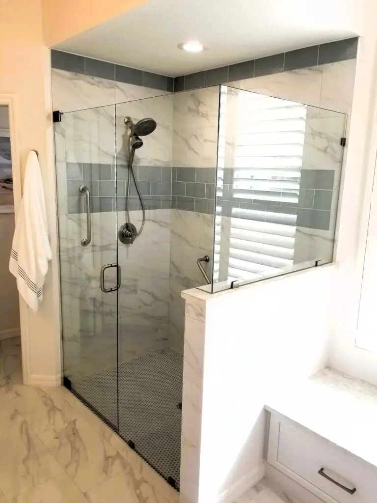 Curbless shower entry with marble styled tile, glass accent tile, and grab bars in a Bradenton home