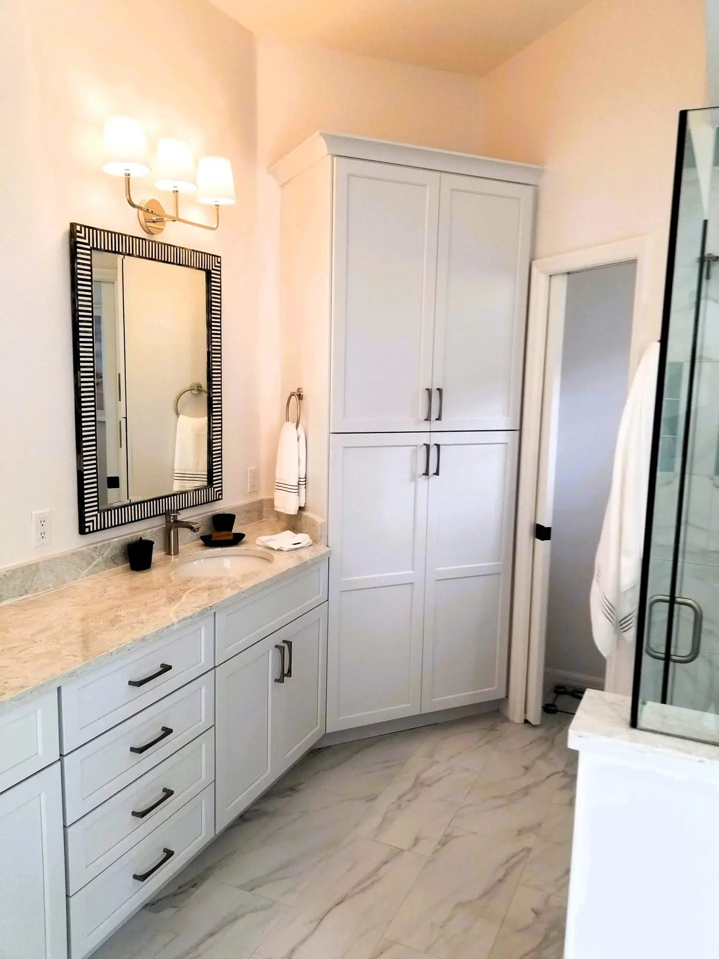Full height white StarMark linen cabinet with Shaker doors for bathroom storage