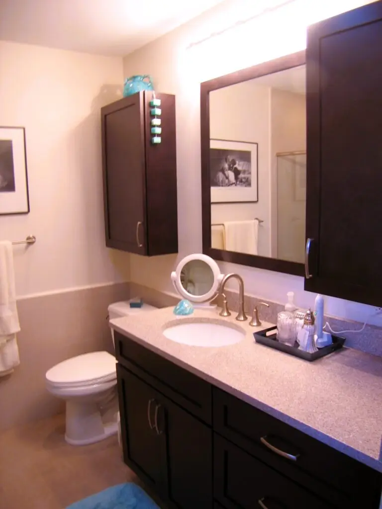After photo of modern dark maple vanity with Cambria counter and framed mirror in Village Green Bradenton bathroom