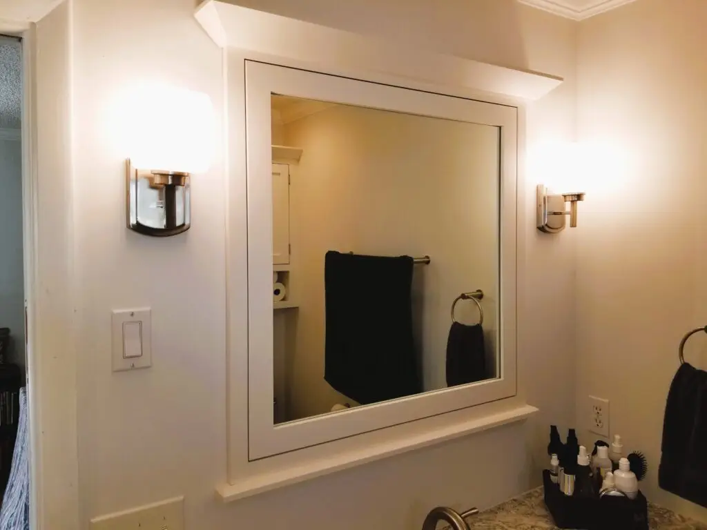 Custom mirror with crown molding and brushed nickel sconces