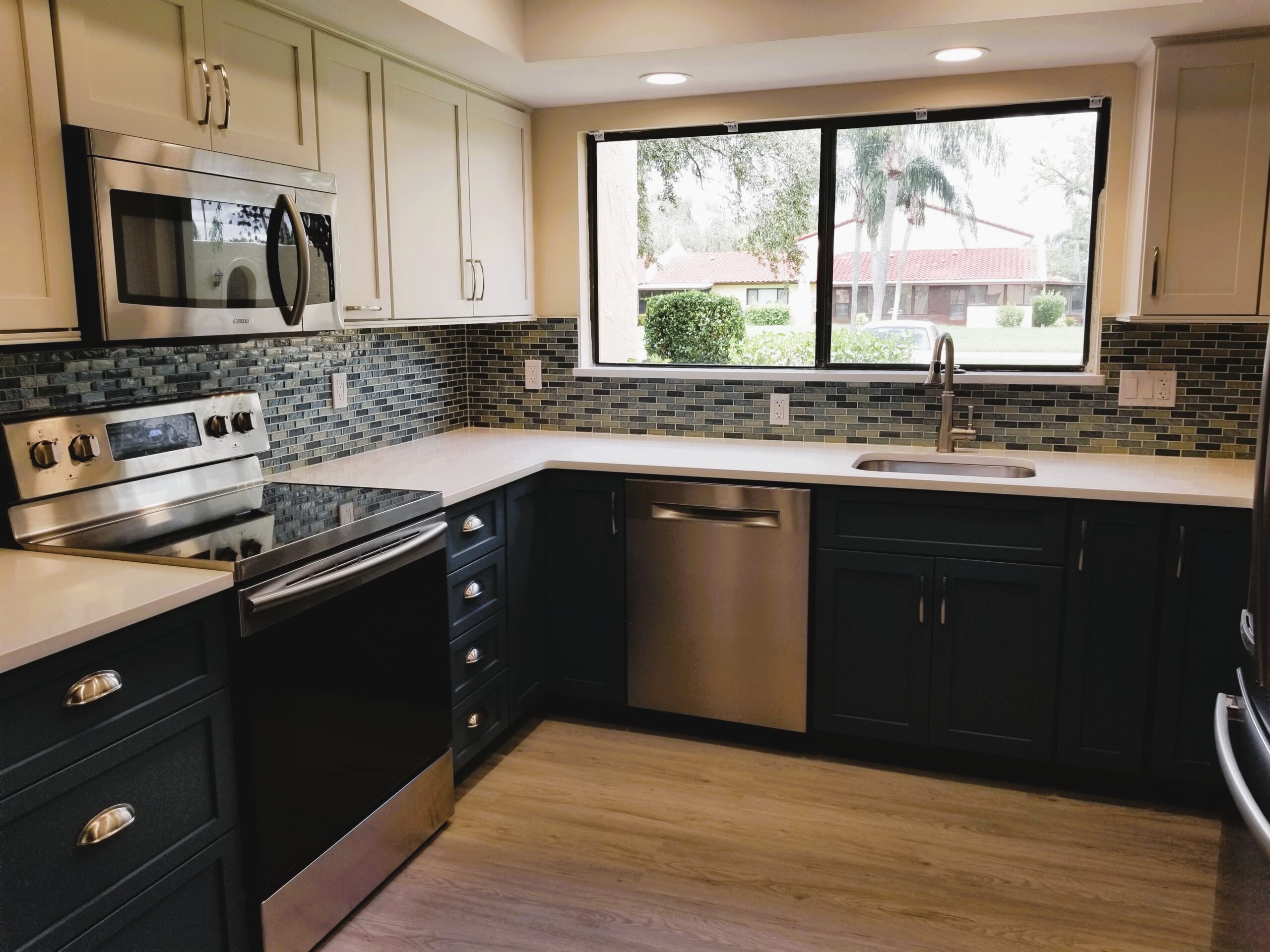 New stainless steel range and microwave in a Meadowcroft condo kitchen with white quartz countertops and glass mosaic backsplash