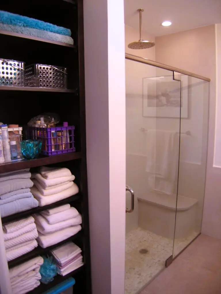 Open shelf maple linen cabinet and curbless shower in newly renovated master bathroom