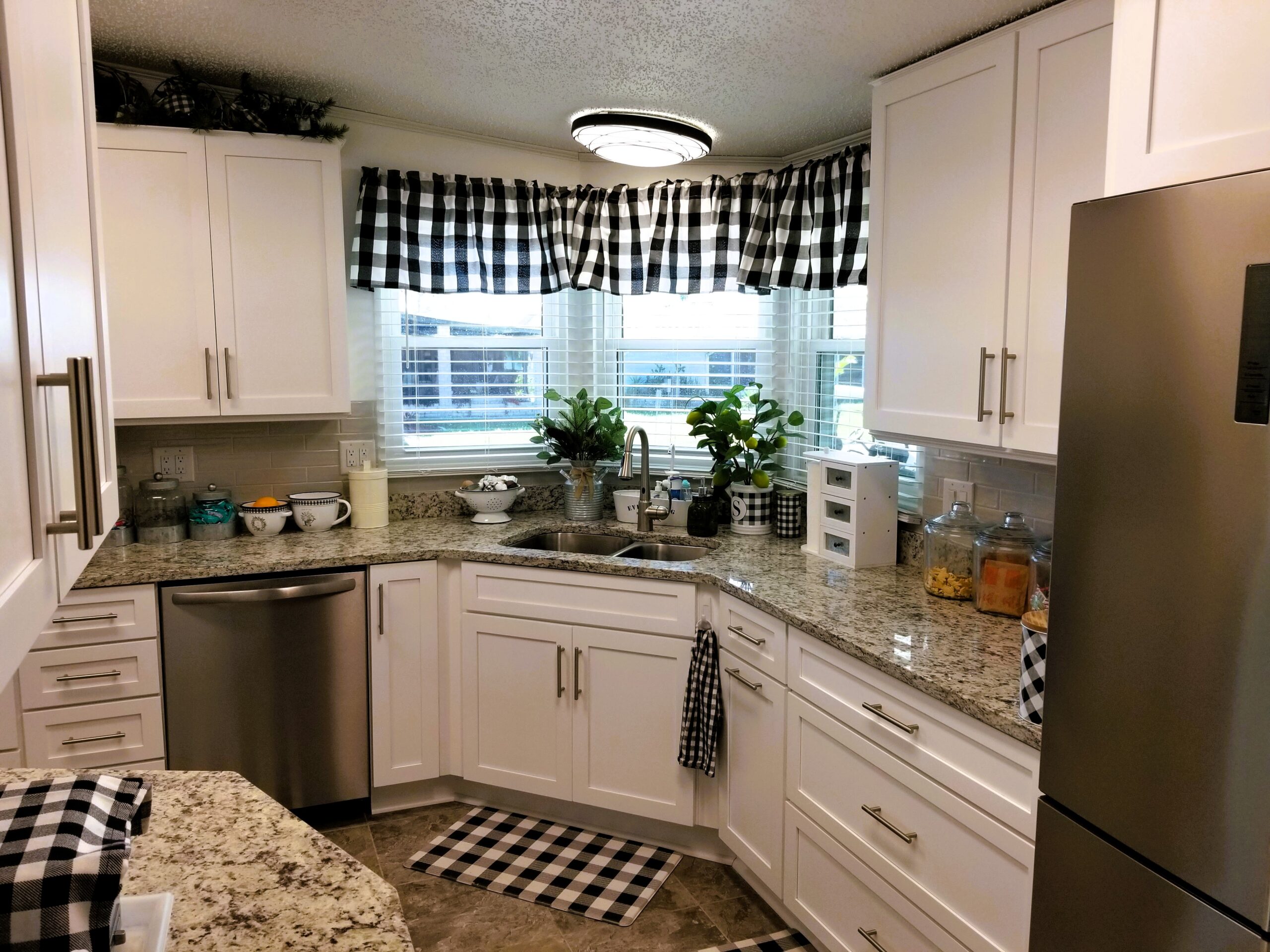 White Ornamental granite countertop and deep kitchen sink detail with black and white buffalo check decor