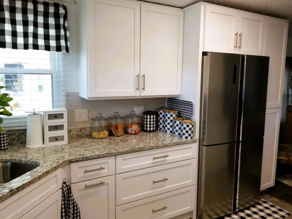 White pantry cabinet with roll out trays next to stainless steel refrigerator