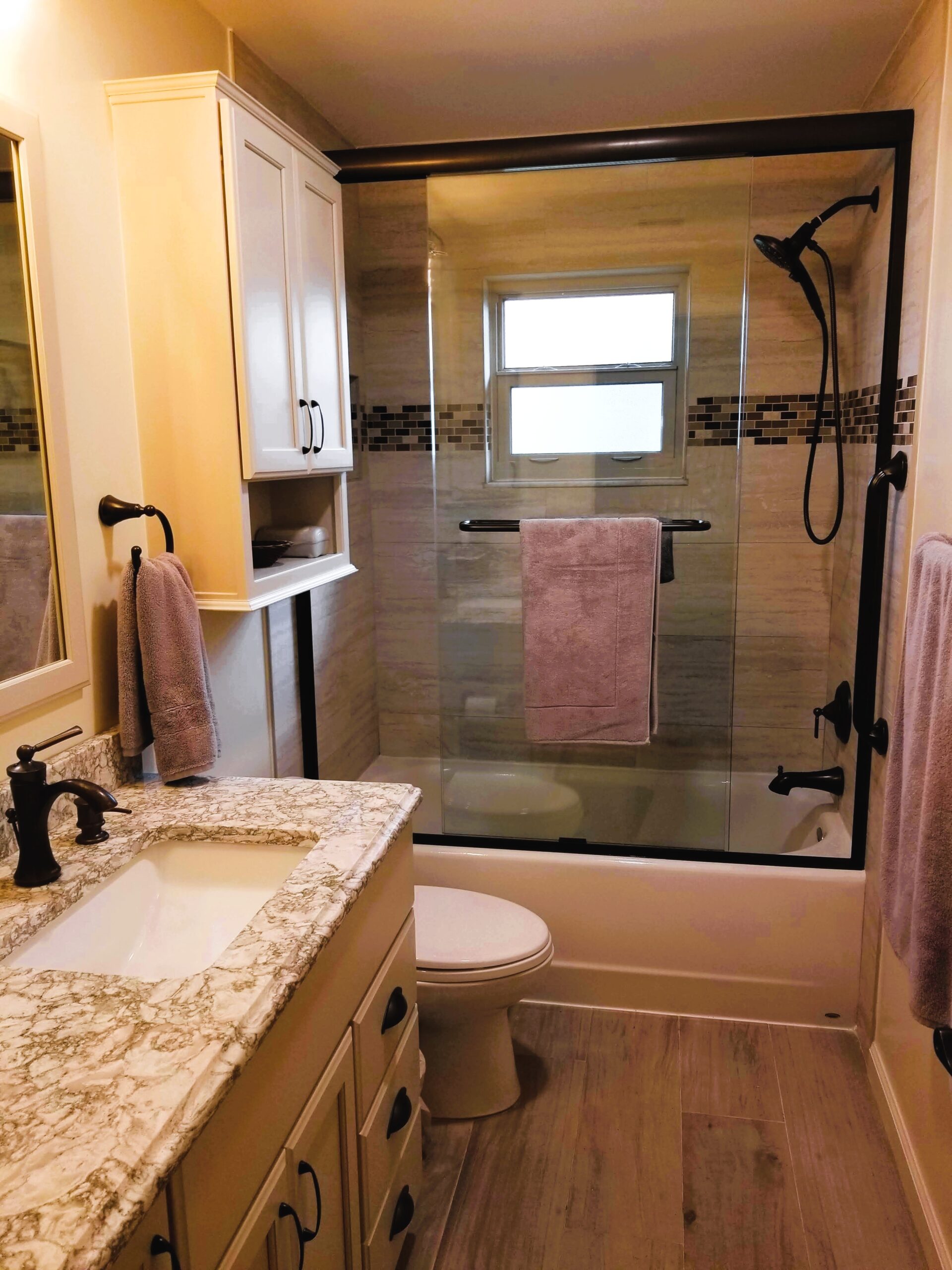 Bathtub with glass sliding doors, oil rubbed bronze fixtures, and taupe subway tile