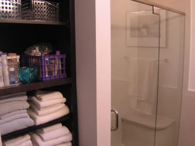 shower with rain head and seat along with open linen shelves, part of a bathroom remodeling project in Bradenton, Florida