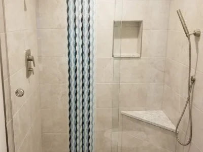 Master bathroom remodel featuring a shower with vertical blue accent tile, seat, niche, and separate handheld spray in Bradenton, Florida